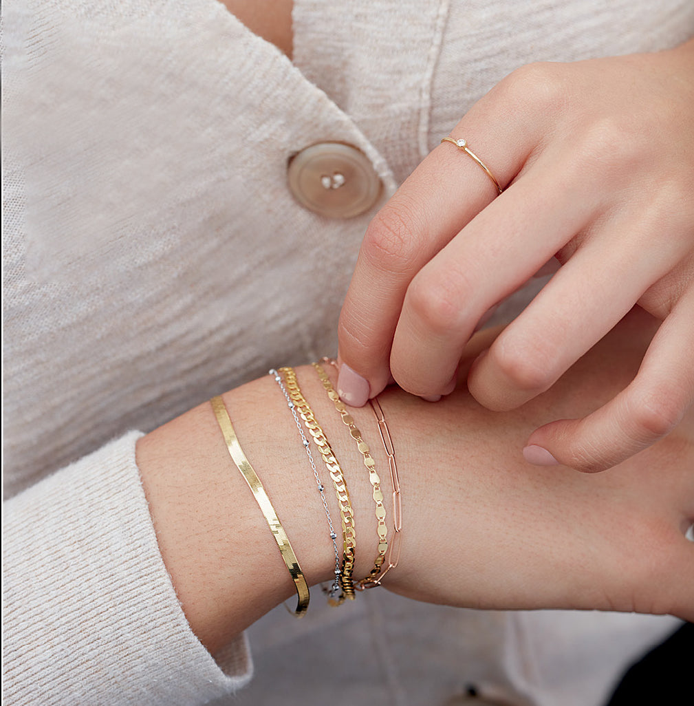 woman wearing a stack of gold chain bracelets